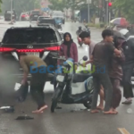 Sepeda motor perempuan terjatuh di belakang mobil hitam di jalan basah Tanjungpinang