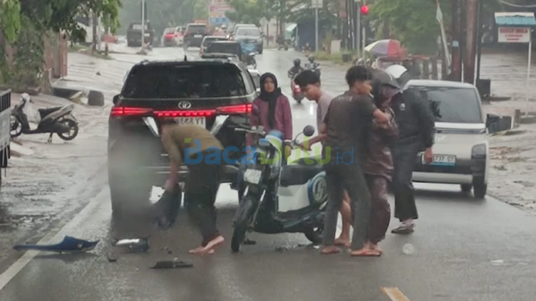 Sepeda motor perempuan terjatuh di belakang mobil hitam di jalan basah Tanjungpinang