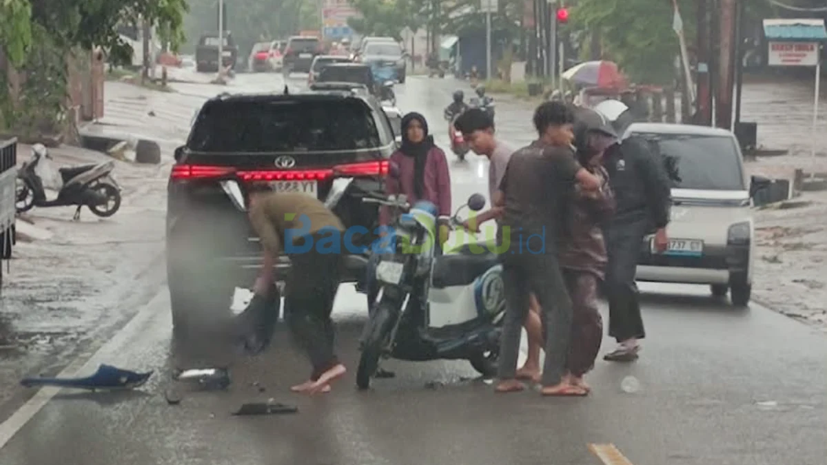 Sepeda motor perempuan terjatuh di belakang mobil hitam di jalan basah Tanjungpinang